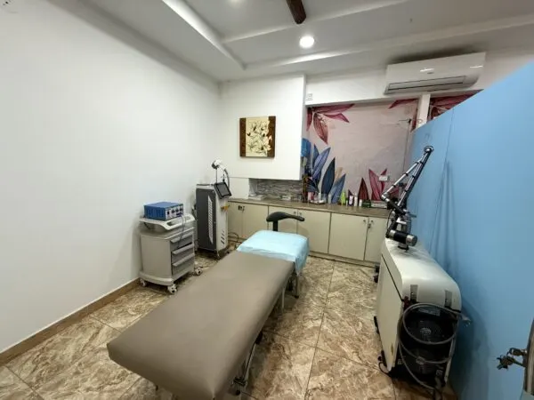 Aesthetic clinic treatment room with a patient bed, laser machines, and clean, modern interior.